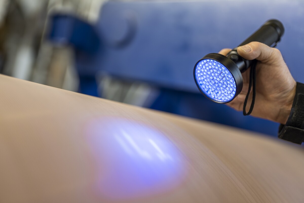 Der QView Pressmantel von Voith macht aufgrund seiner besonderen Eigenschaften und der Verwendung von UV-Licht unsichtbare Risse im Pressmantel sichtbar.
